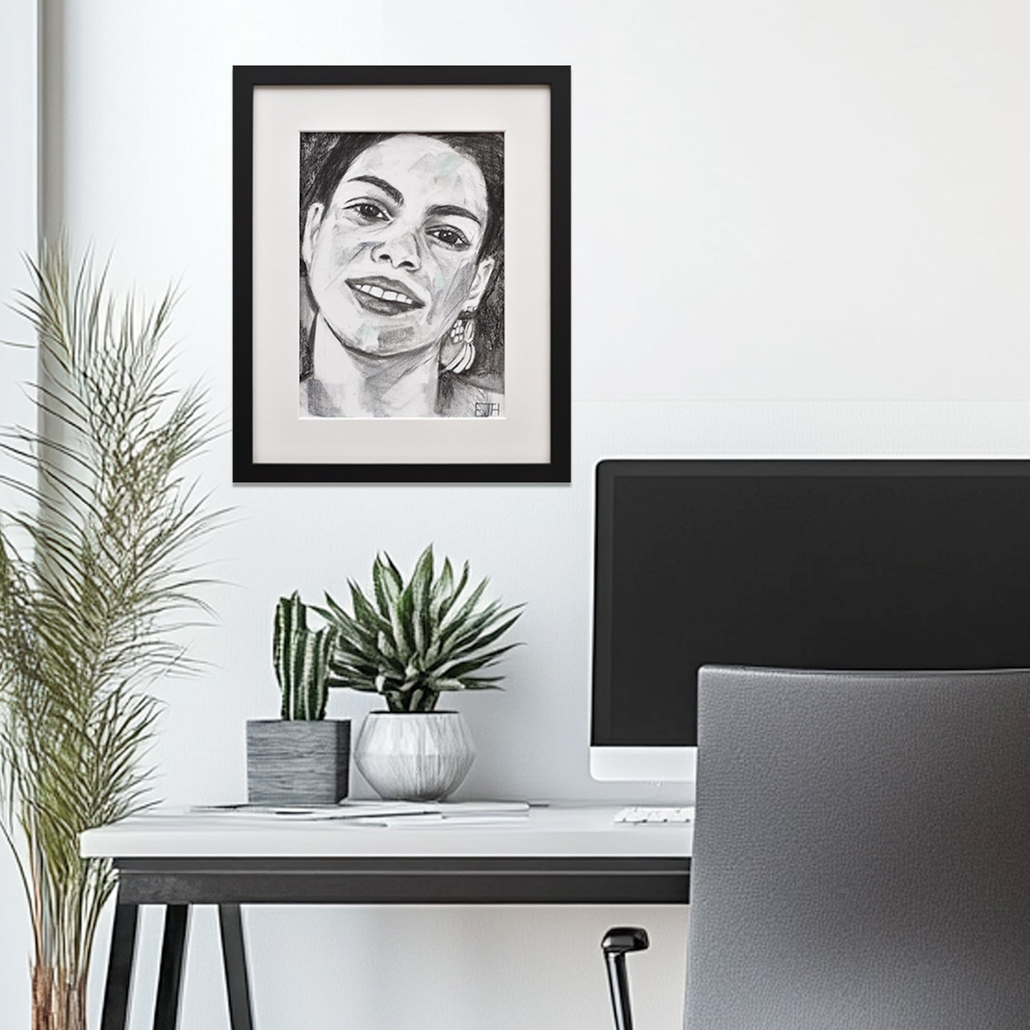 'Charisma' framed portrait drawing hanging above a desk with plants and office furniture.