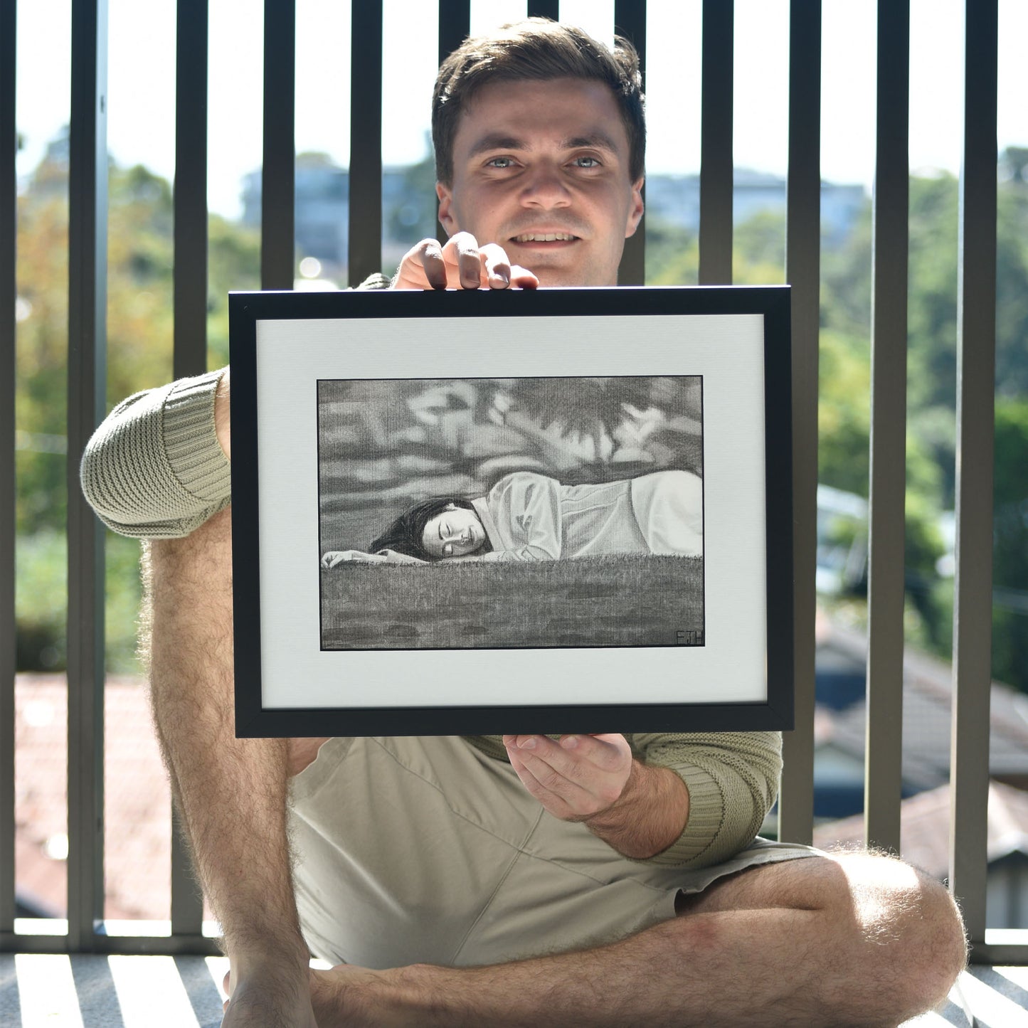 Artist holding 'Passing Of Time', framed drawing portrait.