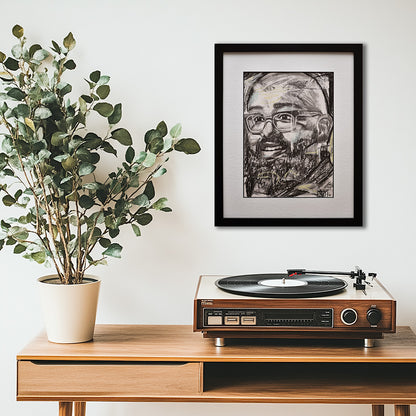 'Amaze' framed portrait drawing hanging above a wooden console table with a turntable and potted plant against a white wall.