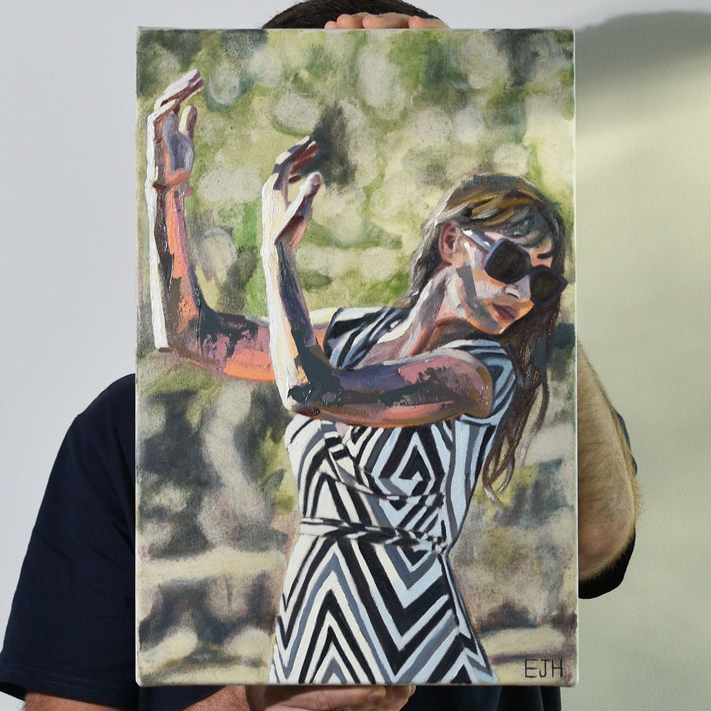 Artist holding an oil painting of a woman in a zigzag dress with black, white and grey colours.
