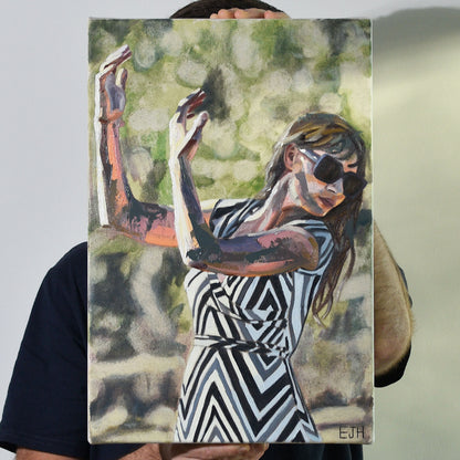 Artist holding an oil painting of a woman in a zigzag dress with black, white and grey colours.