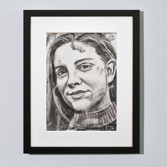 'Believe' framed portrait drawing of a woman with a smile hanging on a neutral wall in the artist's studio.
