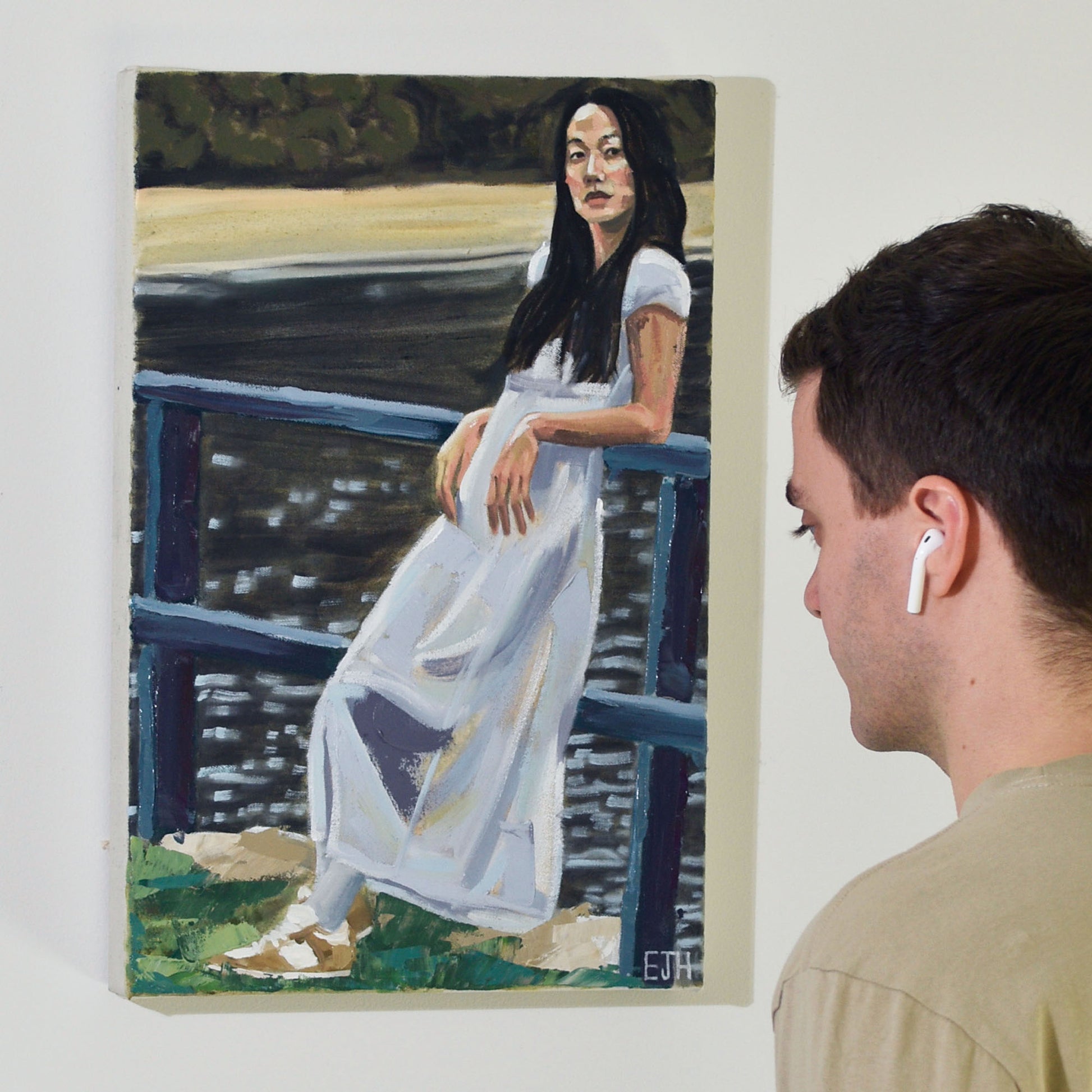 Artist looking at 'Near Lavendar Bay' oil painting of a woman in a white dress by a harbour.