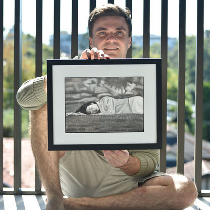 Artist holding 'Passing Of Time', framed drawing portrait.