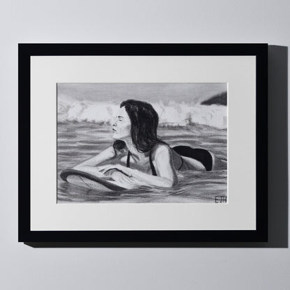 'Soul Surfer' framed portrait drawing of a woman in the ocean hanging on a neutral wall in the artist's studio.