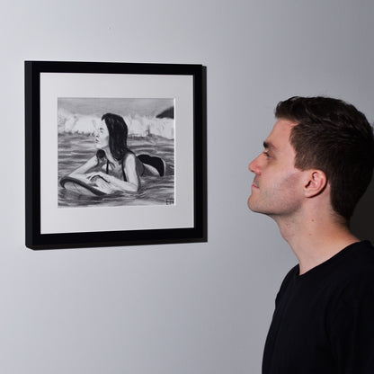Artist looking at 'Soul Surfer', framed drawing portrait on wall.