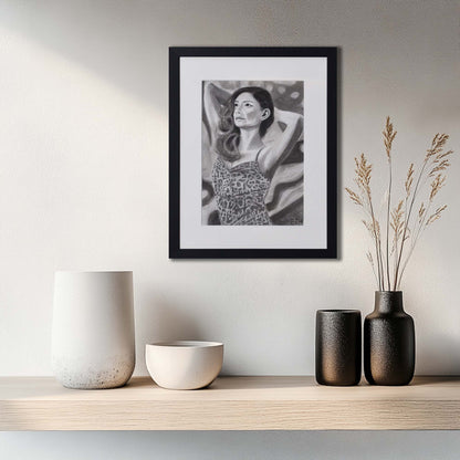 'The Spaces Between Patterns' framed portrait drawing hanging on a wall above a wooden shelf with decorative vases. 